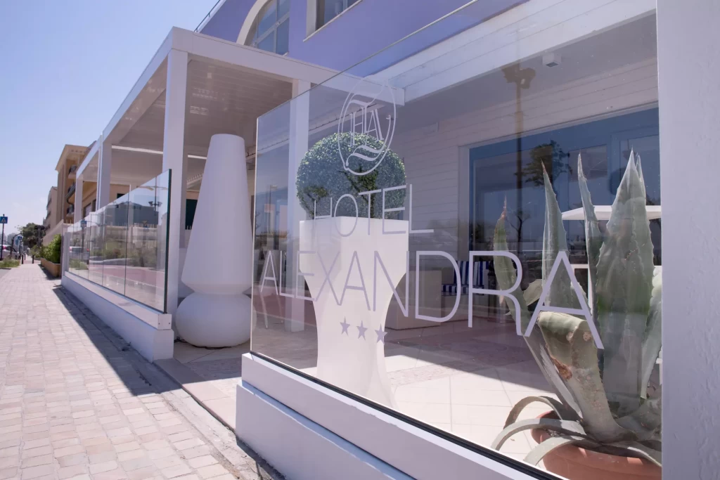 Ingresso dell'Hotel Alexandra con vetrate trasparenti e decorazioni moderne.