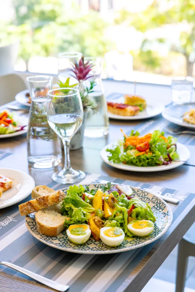 Un tavolo apparecchiato con piatti di insalata, pane, uova sode e bicchieri d'acqua.