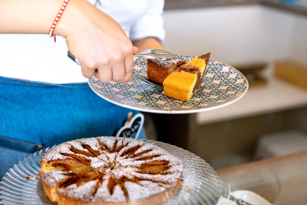 Una persona serve una fetta di torta appena tagliata su un piatto decorato.