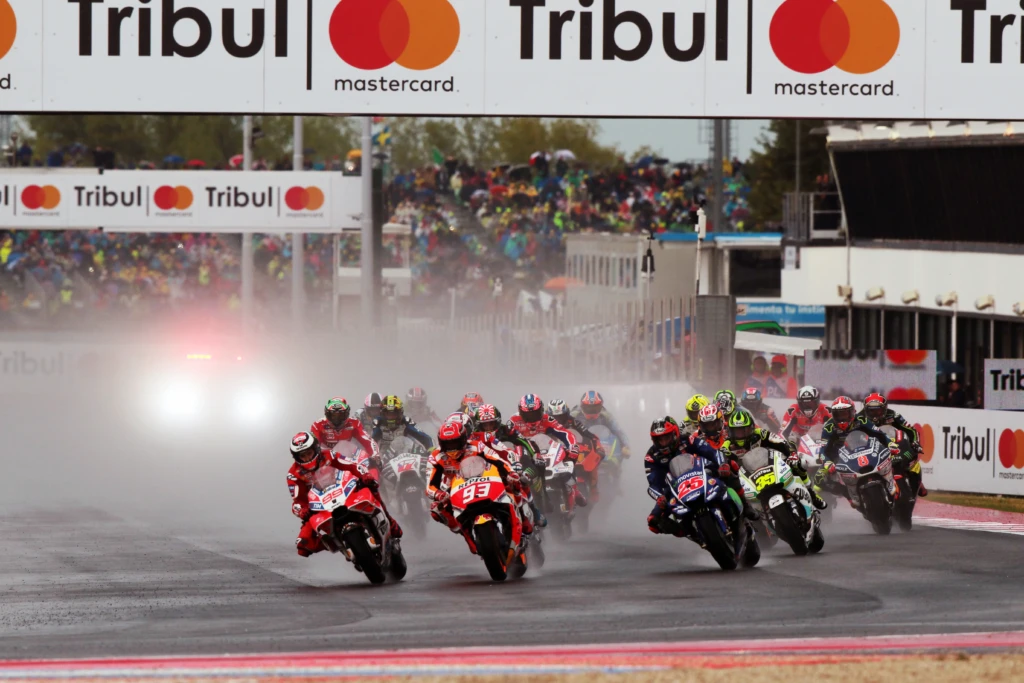 MotoGP, gara sotto la pioggia con piloti che prendono una curva sul circuito.