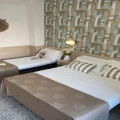 Camera d'albergo con arredi moderni, due letti e carta da parati colorata.