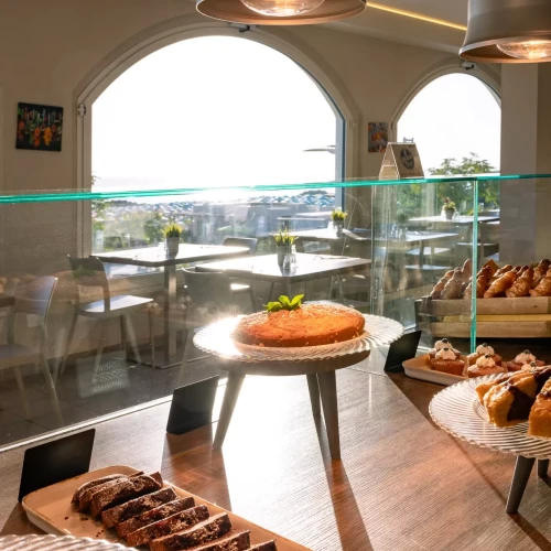 Vetrina di una pasticceria con dolci assortiti illuminati dalla luce del sole.