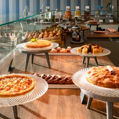 Esposizione di dolci e torte su piatti alti in una pasticceria elegante.