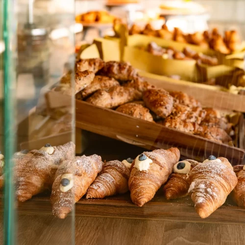 Vetrina di croissant assortiti con decorazioni ai mirtilli in una pasticceria.