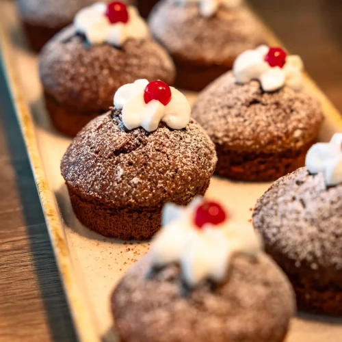 Muffin al cioccolato con panna e ciliegia su un vassoio.