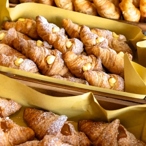 Vassoio di croissant ripieni di crema e marmellata, appena sfornati.