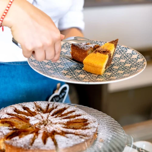 Una persona serve una fetta di torta appena tagliata su un piatto decorato.