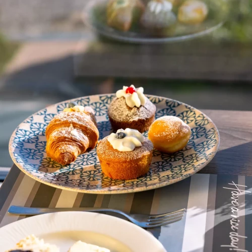 Un piatto di dolci assortiti su un tavolo accanto a fette di pane con marmellata.