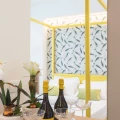 Bottiglie di champagne e calici su un tavolo di fronte a un letto moderno con testiera a motivo fogliare.