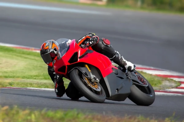 Pilota in piega su una moto rossa durante una gara su pista.